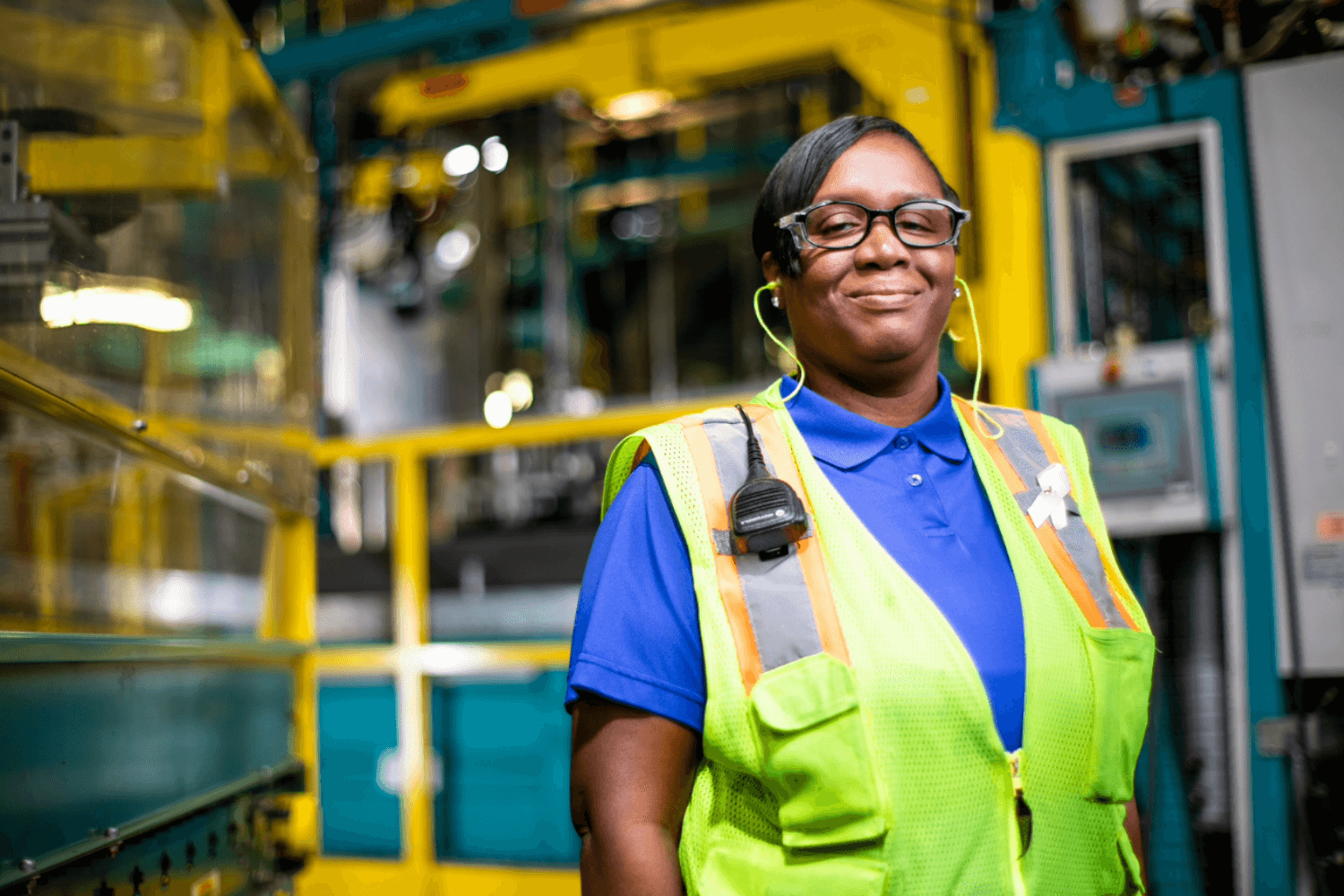 Woman in a yellow vest standing in front of an industrial machine