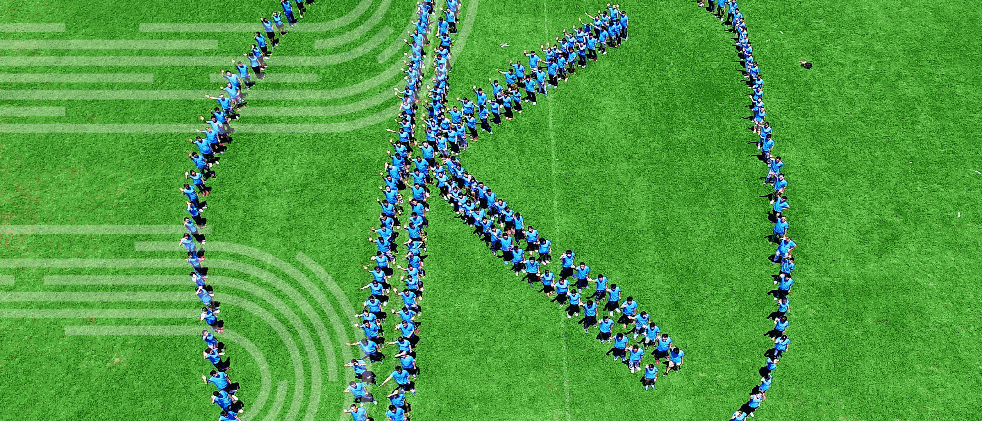 People standing in a green field creating a K surrounded by a circle