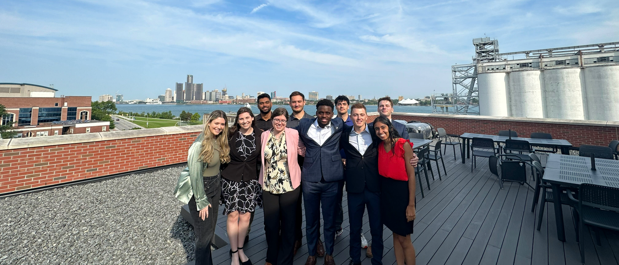 group of people standing on a roof in front of detroit skyline